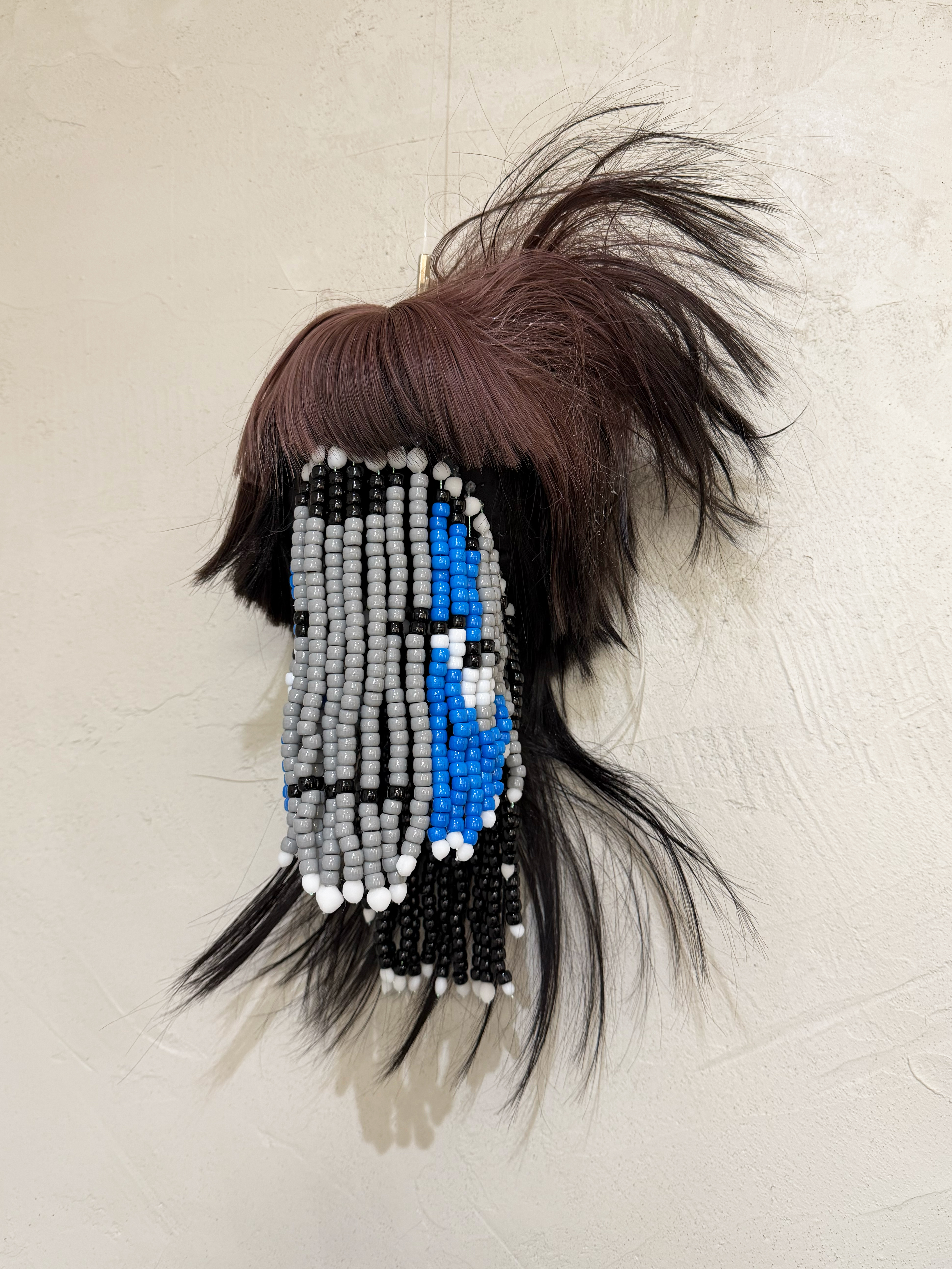 3/4 angle shot of a sculpture made using beads and a sythetic wig to represent a floating head.